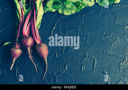 Pile of homegrown organic young beets with green leaves on dark stone table. Fresh harvested beetroots on black concrete background with place for tex Stock Photo