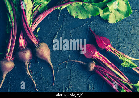 Pile of homegrown organic young beets with green leaves on dark stone table. Fresh harvested beetroots on black concrete background. Top view. Toned i Stock Photo