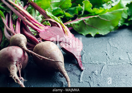 Pile of homegrown organic young beets with green leaves on dark stone table. Fresh harvested beetroots on black concrete background with place for tex Stock Photo
