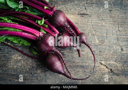 Pile of homegrown organic young beets with green leaves on the table. Fresh harvested beetroots on wooden background with place for text. Rustic style Stock Photo