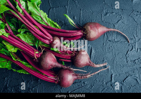 Pile of homegrown organic young beets with green leaves on dark stone table. Fresh harvested beetroots on black concrete background. Top view. Stock Photo