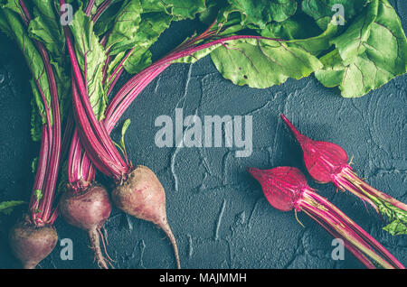 Pile of homegrown organic young beets with green leaves on dark stone table. Fresh harvested beetroots on black concrete background. Top view. Toned i Stock Photo
