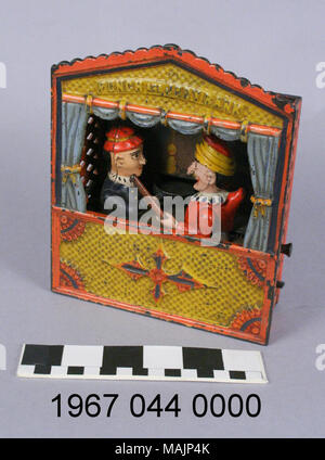 Cast iron mechanical bank depicting a Punch and Judy puppet show. The action is controlled by two levers. the first lever locks the characters in place. To make a deposit, a coin is placed on Judy's tray; a second lever causes Judy to deposit the coin while Punch tries to hit her with a club. Manufactured by the Shepard Hardware Company circa 1884. Title: Punch and Judy Mechanical Coin Bank  . circa 1884. Peter Adams, Jr. (Designer), Charles G. Shepard (Designer), Shepard Hardware Company (Maker), Stock Photo