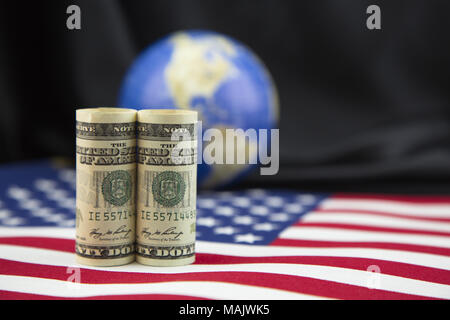 Focus on American currency placed on national flag with unfocused black satin and globe background in shallow depth of field.  Symbols of American pol Stock Photo