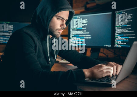 Young man financial hacker at office sitting at table working on laptop to hack system concentrated Stock Photo