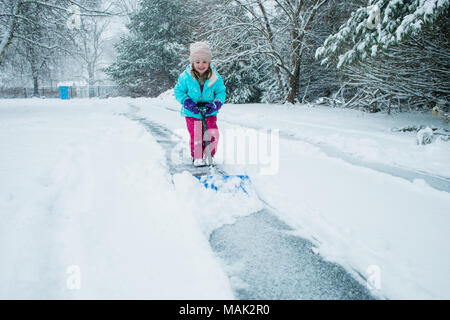 A young girl shoveling snow in a winter storm Stock Photo