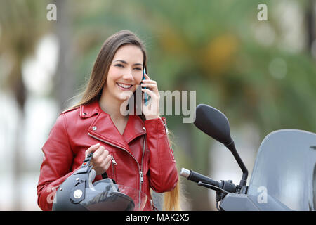 Happy biker calling on smart phone on a motorbike on the street Stock Photo