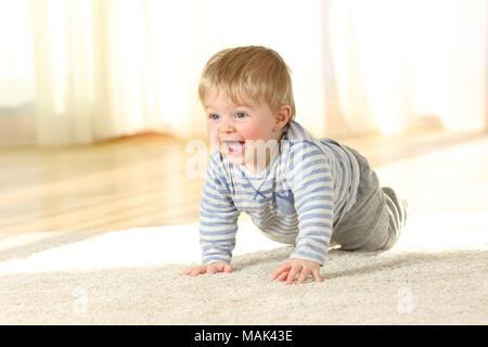 Portrait of a cute baby crawling and laughing on the floor at home Stock Photo