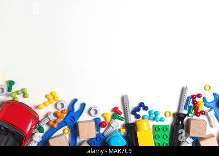 Kids toys background with colorful toy tools, bolts, nuts, car, construction blocks, cubes on white background Stock Photo