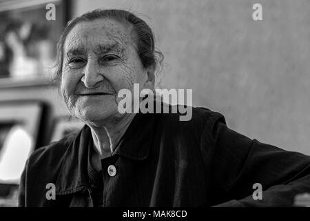 Beautiful 80 plus year old senior woman portrait. Black and white image of elderly woman looking at camera smiling. Stock Photo