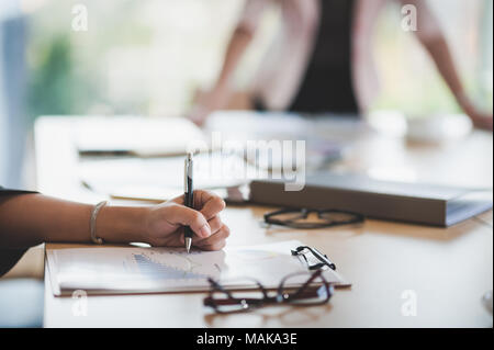 Woman hand writing some idea on clipboard while sitting in meeting room. Business lifestyle on workday Stock Photo