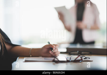 Woman hand writing some idea on clipboard while sitting in meeting room. Business lifestyle on workday Stock Photo