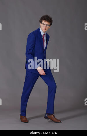 Curly man with glasses wearing in blue suit making step Stock Photo
