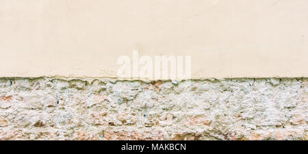 Old weathered vintage brick wall with broken plaster and pavement. Grungy urban background. Stock Photo