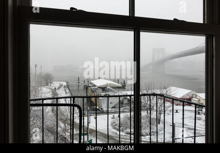 View of a snow storm out a window of a building with a fire escape in Dumbo, Brooklyn Stock Photo