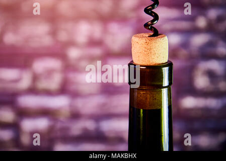 Neck of a bottle of wine with a cork and a corkscrew on the background of a blurry stone wall. Copy space. Stock Photo