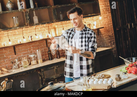 Beautiful young in the morning prepares breakfast for the family and communicates on the Internet with friends. Indoor, studio shot Stock Photo