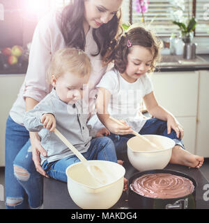Calm mother teaching her children how to bake a cake Stock Photo