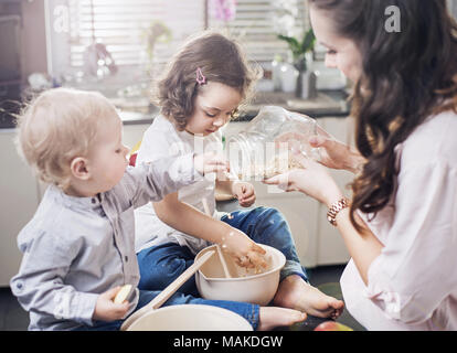 Mother baking a sweet cake with her children Stock Photo