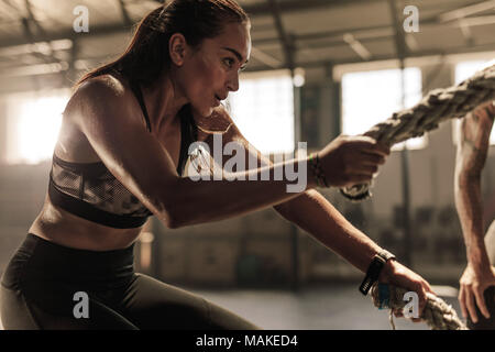 Young woman doing strength training using heavy ropes at the gym. Athlete  moving the ropes in wave motion as part of strength training Stock Photo -  Alamy