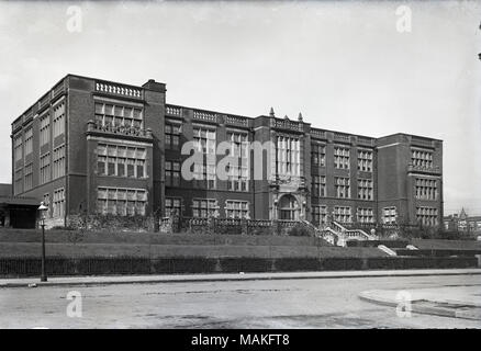 Horizontal, black and white photograph showing a three-story brick building at a three-quarter view. Title: Teachers College, St. Louis.  . November 1915. Oscar Kuehn