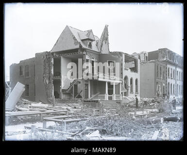 Horizontal, black and white photograph showing destruction in the Lafayette Park neighborhood after a tornado, probably the 1896 tornado. Photograph was probably taken at the corner of Park Avenue and Mississippi Avenue. Five houses have had parts of their roofs, walls, and windows destroyed. An interior staircase of one home can be seen. Piles of rubble and fallen trees can be seen throughout the photograph. Several men are standing amid rubble on the right. Title: Destruction in the Lafayette Park neighborhood after tornado, probably the 1896 tornado.  . 1896.