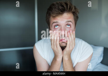 Tired caucasian man sitting on bed. Stock Photo