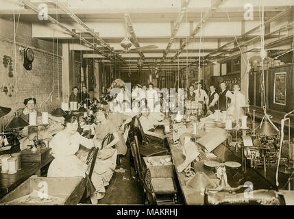 Inscribed on back: 'Work room of A.J. Edlin Mfg. Co. (shirtwaists) Feb. 4, 1919.' Albert J. Edlin was listed as President of the company in the 1919 St. Louis directory. Title: Seamstresses at their stations in the Consolidated Garment Company sewing workshop.  . 4 February 1919. Stock Photo