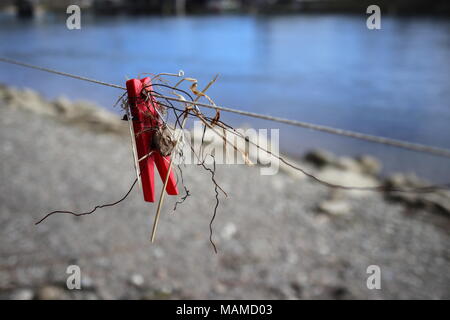 Red clothes peg hanging on a line, combined with wire, outside, shore, shallow depth of field, bokeh Stock Photo