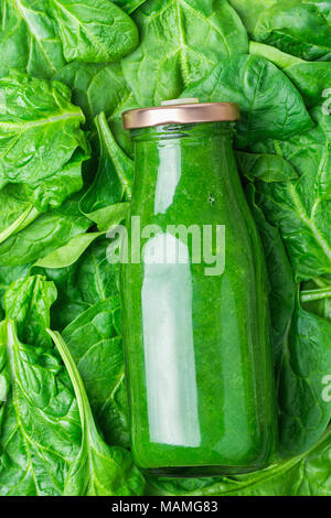 Bottle with Green Fresh Raw Smoothie from Leafy Greens Vegetables Fruits Apples Bananas Kiwi Zucchini on Spinach Leaves as Background. Healthy Lifesty Stock Photo