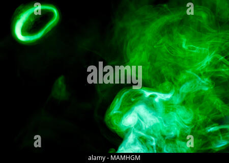 Multi-colored smoke with clubs of green and yellow on a black isolated background Stock Photo