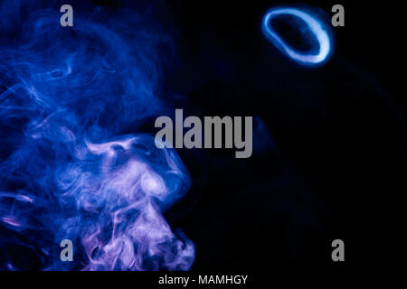 Multi-colored smoke with clubs of blue and purple on a black isolated background Stock Photo