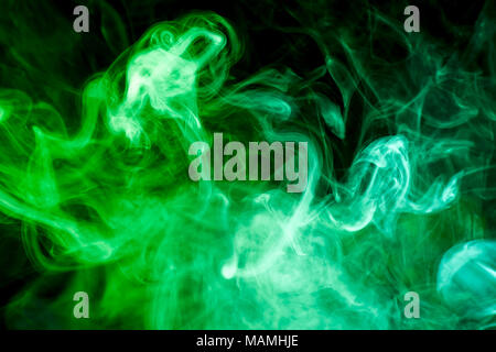 Multi-colored smoke with clubs of green and yellow on a black isolated background Stock Photo
