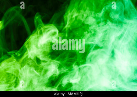 Dense multicolored smoke of  green and yellow colors on a black isolated background. Background of smoke vape Stock Photo