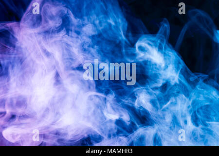 Dense multicolored smoke of  blue and purple colors on a black isolated background. Background of smoke vape Stock Photo