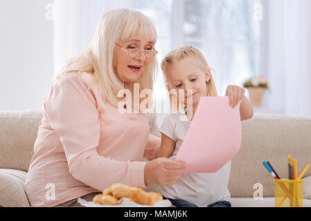 Positive aged woman looking at the drawing Stock Photo