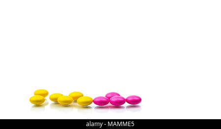 Pile of pink and yellow round sugar coated tablets pills isolated on white background with copy space. Colorful pills for treatment anti-anxiety, anti Stock Photo