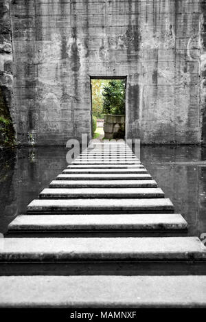 Old bunker or bomb shelter ruin with steps in the water. Abandoned shelter or building, grunge background. Stock Photo