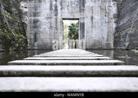 Old bunker or bomb shelter ruin with steps in the water. Abandoned shelter or building, grunge background. Stock Photo