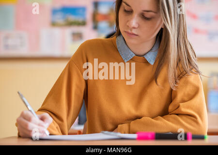 Students taking exam in classroom. Education test and literacy concept. Stock Photo
