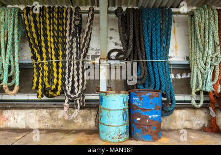 old ropes and oil drums stored on the harbour wall at the cornish fishing port and haven of newlyn in west cornwall. Fishermen related paraphernalia. Stock Photo