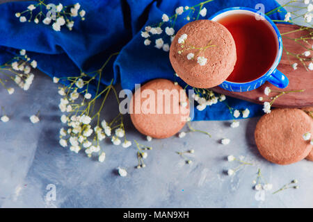 Header with oatmeal cookies, a small blue teacup and linen napkin. Breakfast concept with homemade pastry and spring gypsophila flowers. High key snac Stock Photo