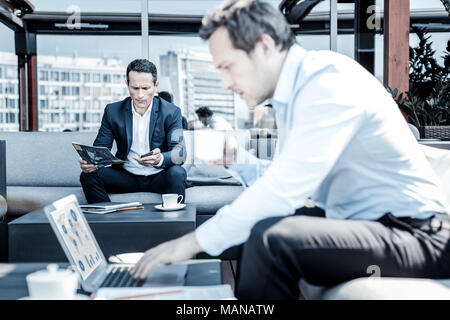 Nice serious businessman using his smartphone Stock Photo