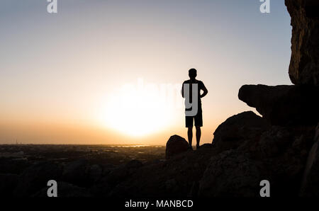 Hiker on the mountain top facing the sunset, silhouette shoot Stock Photo