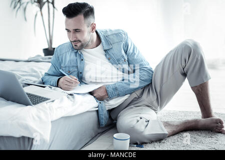 Pleasant cheerful man taking notes Stock Photo
