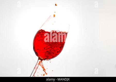 Red wine being poured in a glass and splashed around Stock Photo