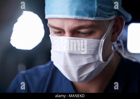 Male surgeon looking down, head and shoulders
