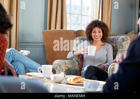 Middle Aged Woman Meeting Friends Around Table In Coffee Shop Stock Photo