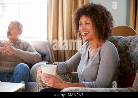 Middle Aged Couple Meeting Friends Around Table In Coffee Shop Stock Photo