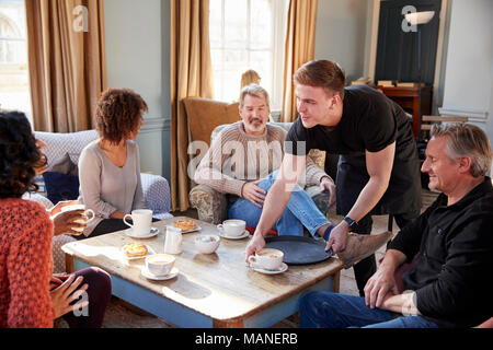 Waiter Serving Group Of Mature Friends In Coffee Shop Stock Photo